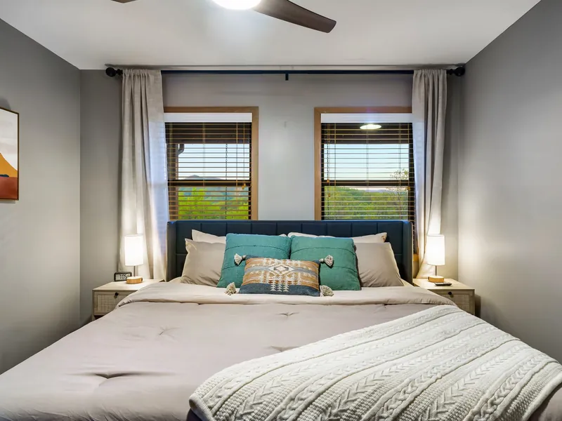 King bed between two mountain-view windows in a main-floor bedroom at the cabin