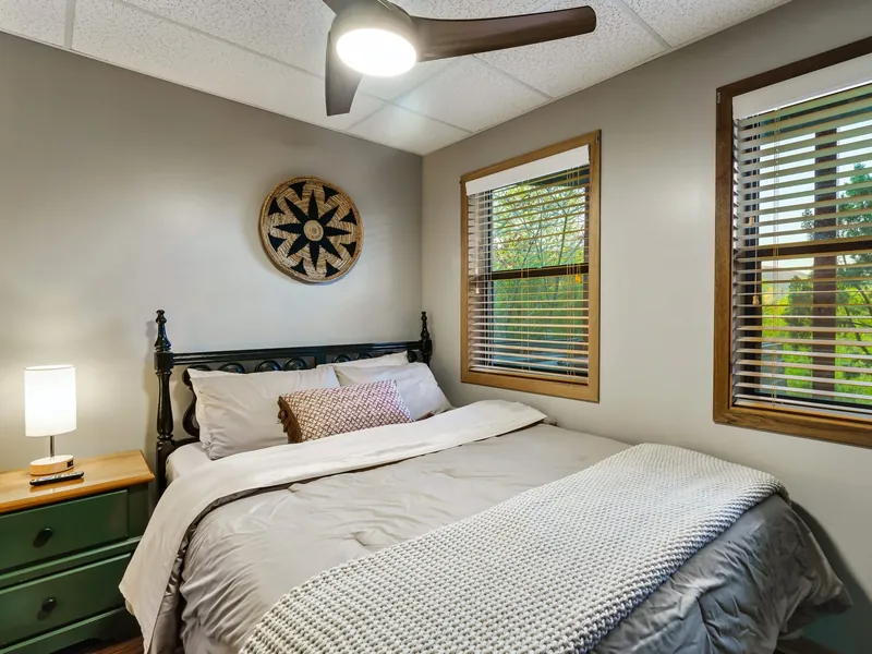 Queen bedroom on the cabin's lower level with two windows and a green nightstand